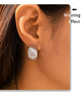 Close-up of a silver C-shaped twill earring on ear showing the refined metal texture