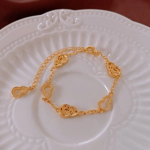 Gros plan détaillé du bracelet double gourde dorée avec motifs ajourés sur assiette blanche
