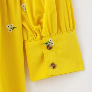 French country style yellow dress with floral embroidery and buttoned cuffs close-up