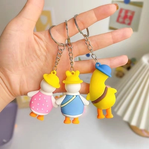 Three cute silicone cartoon duck keychains in various colorful outfits with metal rings