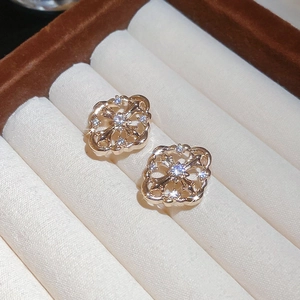 Macro detail of rose gold geometric cross earrings with zircons in a beige jewelry box
