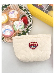 Dettaglio della borsa cosmetica trapuntata crema con ricamo a cuore e zip resistente