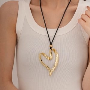 Macro shot of large golden irregular heart pendant on a black cord for women