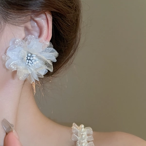 Macro detail of elegant layered white mesh flower earring with pearl center on model