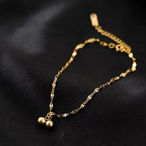 Elegant gold titanium steel bracelet with two polished ball charms on a dark background