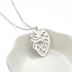 Silver anatomical heart pendant necklace in a white ceramic petal dish with a fine chain