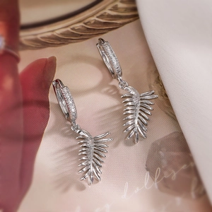 Close-up of silver leaf-shaped earrings with sparkling cubic zirconia on floral background