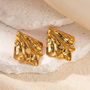 Gold stainless steel irregular wrinkled earrings on white rock and champagne silk background