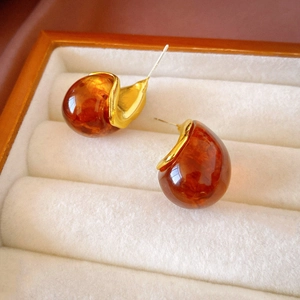 Gros plan de boucles d'oreilles goutte en résine ambre et métal doré sur velours