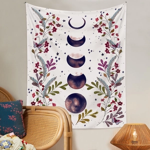 Tenture bohème phases de lune et fleurs suspendue au-dessus d'un fauteuil en rotin