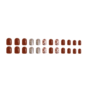 Detail view of reddish brown press-on nails with golden glitter and floral patterns