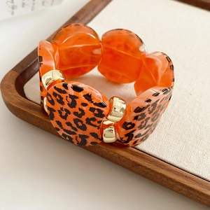Detail of leopard print resin links with gold metal connectors on an elastic bracelet