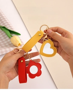 Close-up of heart and flower-shaped PU leather mirror keychains with gold metal clasps