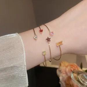 Gold open bangles set with colorful zircon stones in star, heart, and square shapes