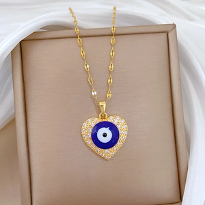 Close-up of golden heart pendant with blue evil eye and zircons on a jewelry box