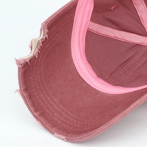 Close-up of distressed brim detail on washed cotton baseball cap in dusty pink