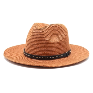 Detail of tan woven straw fedora hat featuring a black faux leather band with gold studs