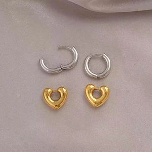 18K gold-plated heart-shaped hoop earrings and silver circular rings on silk fabric