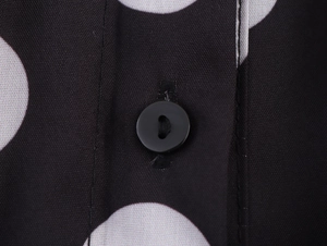 Makro-Detail des schwarzen Knopfes auf dem schwarz-weißen Vintage-Polka-Dot-Stoff