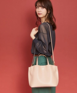 Asian model wearing a pale pink PU leather handbag against a deep red background