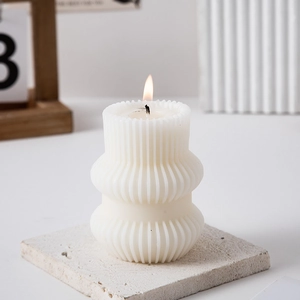 Macro shot of white geometric pillar candle with vertical stripes on a stone base