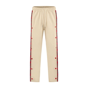 Detail of beige joggers featuring red plaid side panels and snap button fasteners