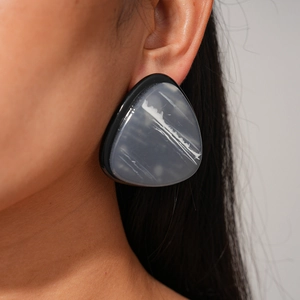 Macro shot of geometric resin triangle earring featuring grey marble pattern and black edges