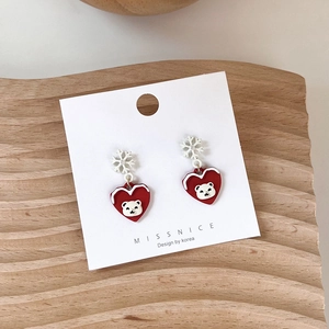Detailed close-up of heart-shaped Christmas earrings with bear and snowflake motifs