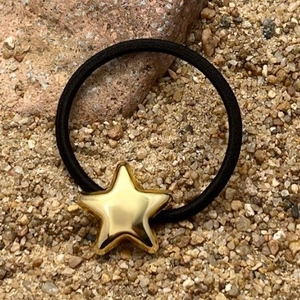 Minimalist black elastic hair tie featuring a polished gold star metal charm accessory
