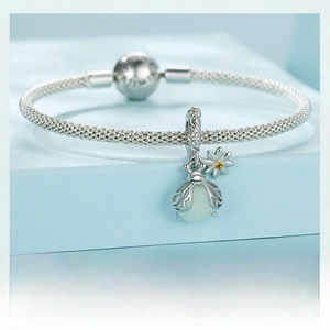 Detail of s925 silver bracelet featuring a bee charm with green gemstone and daisy charm