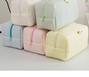 Dettaglio di cinque trousse in maglia color pastello con fiori e trame a diamante