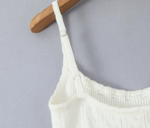 Détail de robe en tricot blanc montrant les bretelles réglables et le col en dentelle