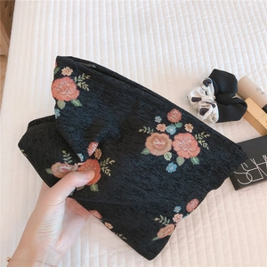 Detail of vintage jacquard fabric and floral embroidery on a large capacity cosmetic bag