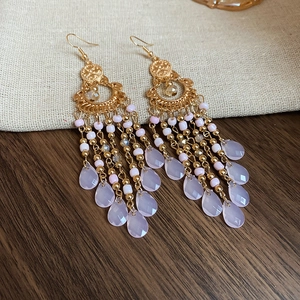 Detailed view of bohemian gold earrings with purple beads and teardrop crystal tassels