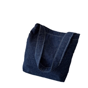 Dark blue denim tote bag with nep texture and white contrast stitching on white background