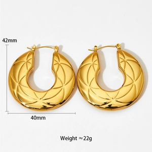 Macro view of gold-plated hollow hoop earrings featuring radial geometric engravings and size details