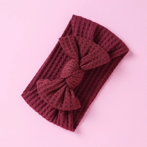 Detailed view of maroon waffle-knit baby headband with bow knot on pink background