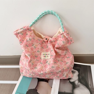 Dettaglio della borsa floreale rosa con manico in corda intrecciata e chiusura a scatto