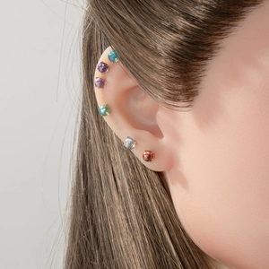 Polished dragon ball stud earrings in multiple vibrant colors on model's ear