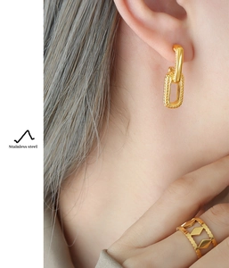 Close-up of golden stainless steel U-shaped earrings and镂空 ring on a model