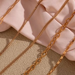 Detailed view of various 18K gold plated stainless steel chain styles on silk background