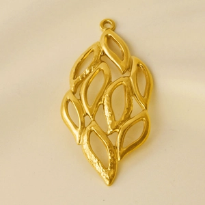 Close-up of golden hollow leaf pendant made of 304 stainless steel on beige fabric