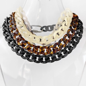 Close-up of thick acrylic link necklaces in cream, tortoiseshell and black on clear bust