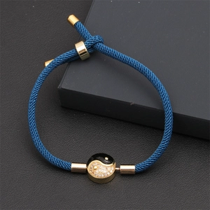 Macro detail of navy blue woven bracelet with golden yin yang charm and zircon stones