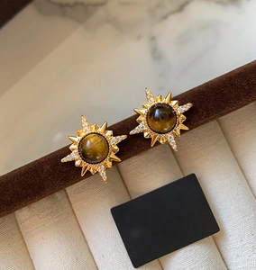 Détail macro de boucles d'oreilles étoile plaquées or 18 carats avec œil de tigre