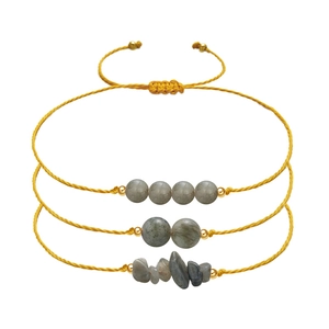 Detail of three-piece labradorite stone bracelets with yellow woven cords and gold beads