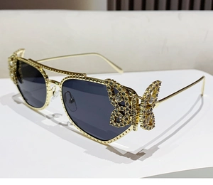 Detailed butterfly hinge design on gold metal frame sunglasses with crystal accents