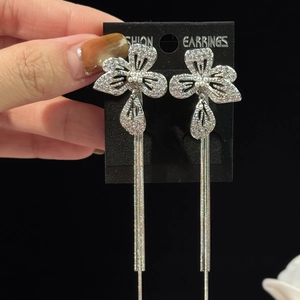Gros plan sur des boucles d'oreilles fleur argent avec de longs pompons et des cristaux