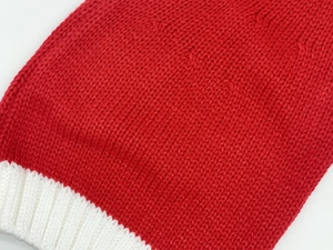 Gros plan sur la texture tricotée rouge et blanche et les côtes du bonnet de Noël