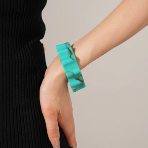 Detail of wide resin bangle featuring artistic turquoise marble texture on model's wrist